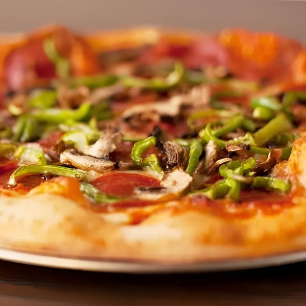 Close-up of a pepperoni, mushroom, and green pepper pizza from Wings Things & Pizza.