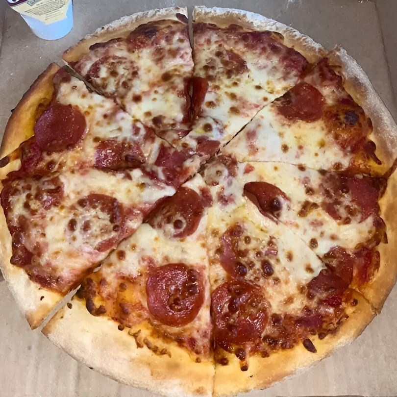 A whole pepperoni pizza from Wings Things & Pizza, cut into eight slices, in a cardboard box.