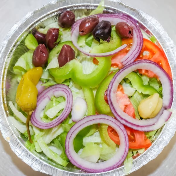 Fresh garden salad with lettuce, tomatoes, red onions, green peppers, olives, and a pepperoncini.